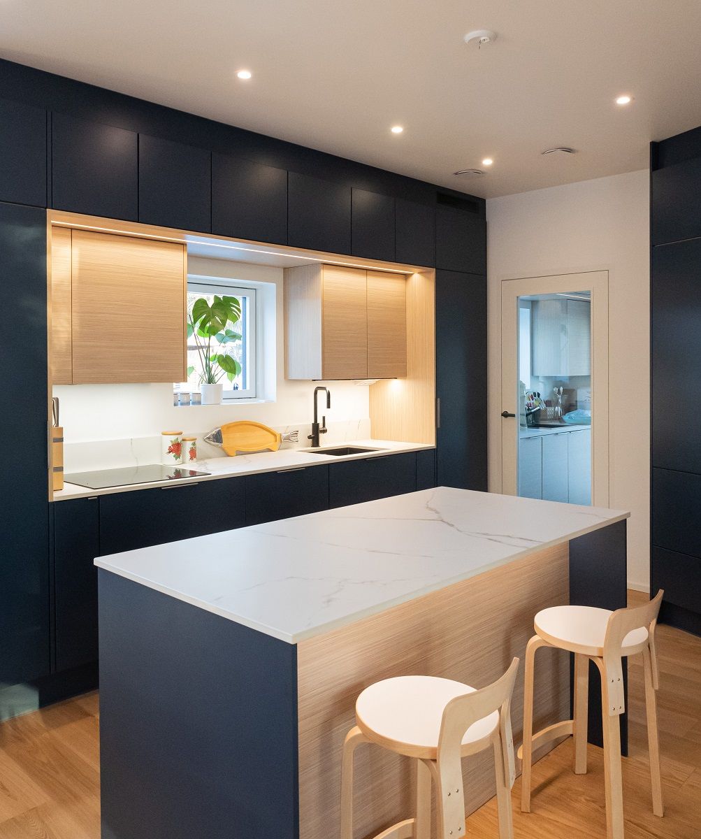 I faretti a soffitto, disposti in modo uniforme, illuminano anche l'isola della cucina. Il bordo anteriore dell'isola è illuminato verso il basso da una striscia LED in un profilo di alluminio.